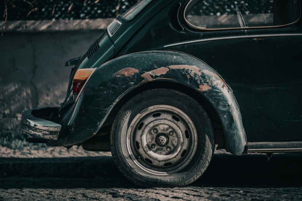 Close-up of a weathered classic Volkswagen Beetle, showcasing its worn paint and nostalgic appeal.