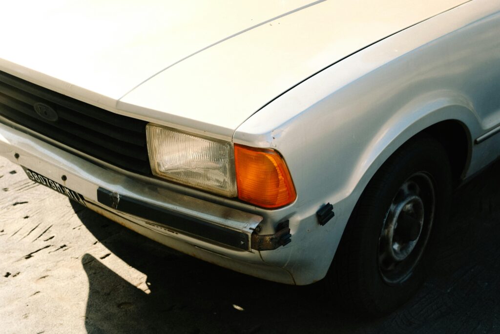 Detailed view of a classic white car front with vintage headlight and grille.