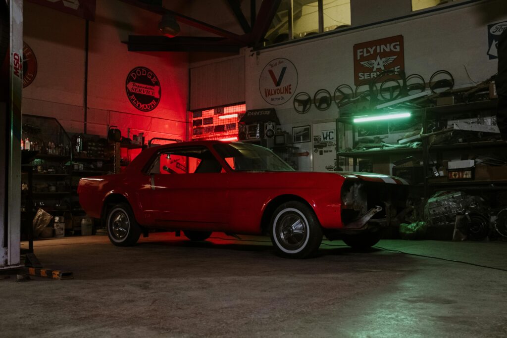 Vintage red car in an atmospheric auto shop with neon lights and vintage signs.