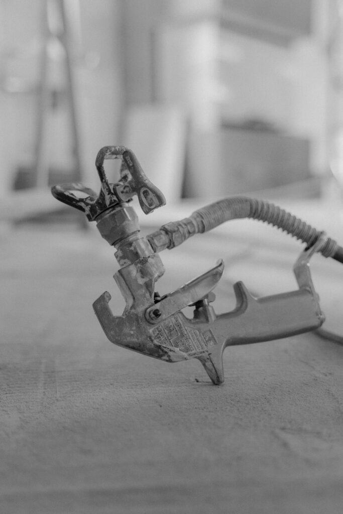 Monochrome close-up of a spray gun on a blurred background. Industrial focus.